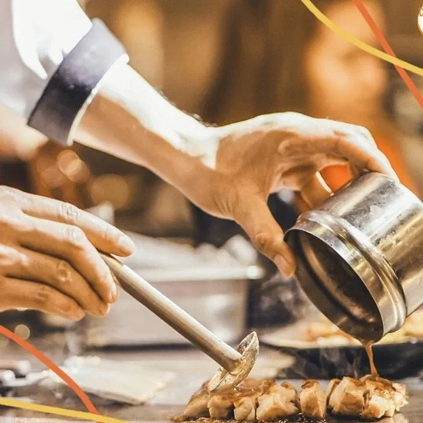 Chef preparing grilled chicken with sauce in a professional kitchen – showcasing culinary expertise and dedication to quality.